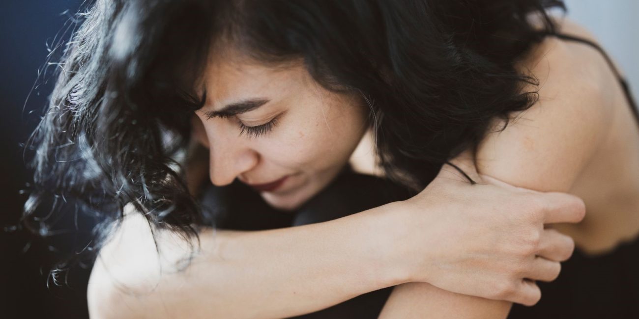 Femme triste qui croise les bras tête baissée