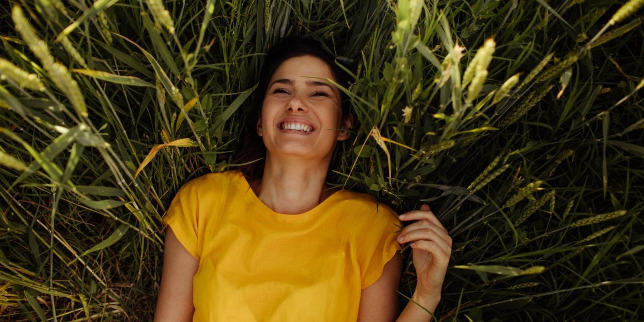 Femme souriante allongée dans l'herbe