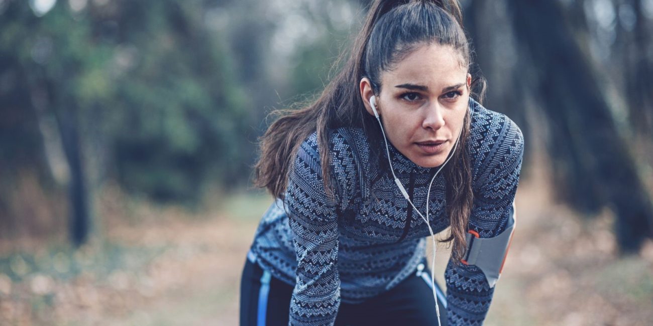 Femme en tenue de sport dans une forêt regardant au loin