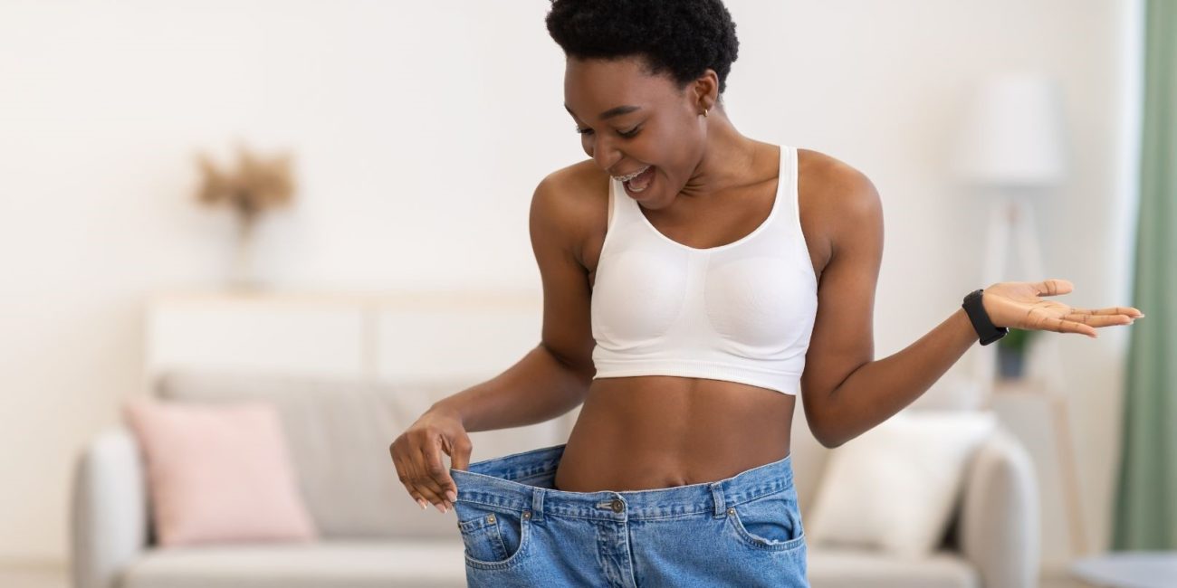 Femme qui montre sa perte de poids avec un pantalon trop grand